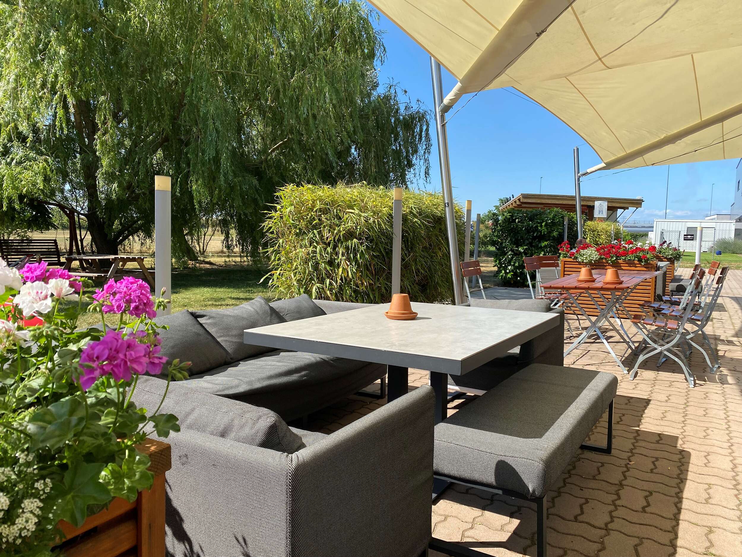 Marché Schwechat Terrasse mit Sonnenschirm und Blumen